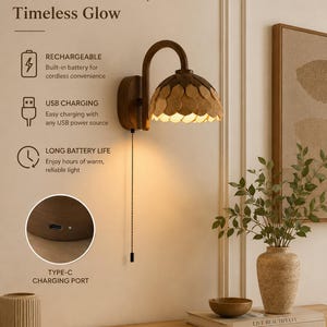 Puede incluir: Una lámpara de pared con brazo de madera curvado y pantalla en capas con forma de pétalos en tonos madera claros y oscuros. Incluye cadena de tiro, batería recargable y puerto de carga USB tipo C. Texto: Cordless Freedom, Timeless Glow.