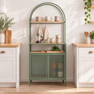 May include: A sage green metal baker's rack with an arched top, featuring two wooden shelves, a hanging rod with two striped kitchen towels, and a lower cabinet with two mesh doors. The unit holds several ceramic mugs and a glass French press.