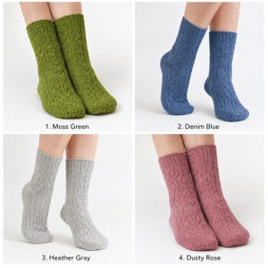 May include: A set of four pairs of mid-calf knit socks featuring a vertical cable knit pattern. The socks are available in four distinct solid colors: moss green, denim blue, heather gray, and dusty rose, each with a ribbed cuff at the top.