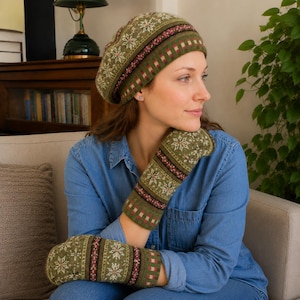Könnte beinhalten: Eine gestrickte olivgrüne Baskenmütze und passende Fäustlinge mit einem detaillierten weißen Schneeflockenmuster, horizontalen Streifen in Dunkelrot und Creme sowie einem gerippten Bündchen. Das Set ist durchgehend im Fair-Isle-Strickmuster gefertigt.