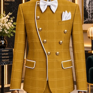 May include: A mustard yellow plaid blazer with a mandarin collar, white piping, and gold-toned buttons. The jacket features an asymmetrical front closure, a white bow tie, and a white pocket square. The design includes long sleeves and two flap pockets.