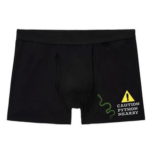 Peut inclure: Un cale&ccedil;on noir avec un motif sur le c&ocirc;t&eacute; inf&eacute;rieur droit. Le motif comprend une illustration de serpent vert &agrave; c&ocirc;t&eacute; d'un panneau d'avertissement triangulaire jaune avec un point d'exclamation et le texte CAUTION PYTHON NEARBY en blanc.