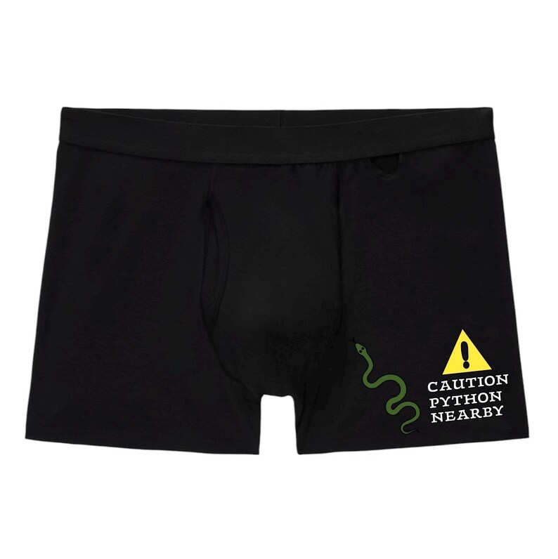 Peut inclure: Un cale&ccedil;on noir avec un motif sur le c&ocirc;t&eacute; inf&eacute;rieur droit. Le motif comprend une illustration de serpent vert &agrave; c&ocirc;t&eacute; d'un panneau d'avertissement triangulaire jaune avec un point d'exclamation et le texte CAUTION PYTHON NEARBY en blanc.