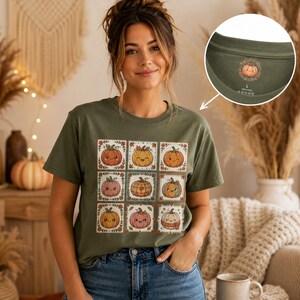 Peut inclure: Un t-shirt vert olive arborant une grille de neuf citrouilles illustrées avec diverses expressions faciales et des bordures de feuilles d'automne. L'étiquette intérieure du col affiche un petit motif de citrouille, la taille L et 100% Cotton.