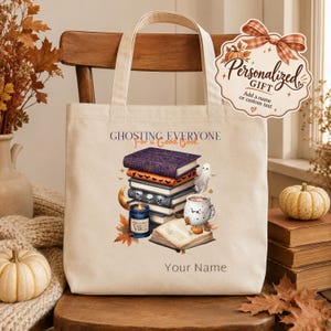Peut inclure: Un sac fourre-tout en toile crème avec une illustration d'une pile de livres, un fantôme, une bougie et une tasse. Le texte indique GHOSTING EVERYONE For a Good Book et Your Name. Une étiquette décorative indique Personalized Gift.