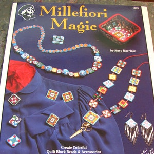 May include: A magazine cover titled "Millefiori Magic" displays colorful handmade jewelry and accessories. The image features a necklace, earrings, and brooches with geometric patterns. The text reads "Create Colorful Quilt Block Beads & Accessories using Oven-Bake Clay and this Age-Old Technique!"