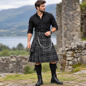Peut inclure: Une chemise noire à manches longues boutonnée associée à un kilt à carreaux gris et noir. Le kilt présente une poche cargo latérale, des détails en métal argenté et une chaîne décorative à trois rangs. Des chaussettes hautes et des bottes noires.