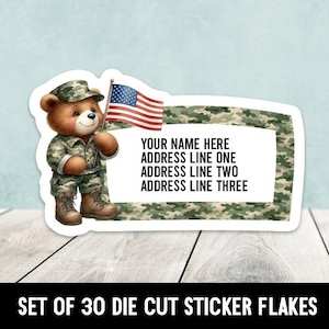May include: A die-cut sticker featuring a teddy bear in a camouflage uniform holding an American flag. The sticker includes a white rectangular space for personalization with the text "YOUR NAME HERE" and address lines. The bottom text reads "SET OF 30 DIE CUT STICKER FLAKES."
