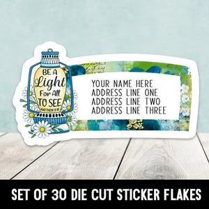 Pode incluir: Um autocolante recortado com um design de lanterna azul e o texto "BE A Light For All TO SEE Matthew 5:16". O autocolante também inclui espaço para um nome e endereço. A parte inferior do autocolante diz "SET OF 30 DIE CUT STICKER FLAKES".