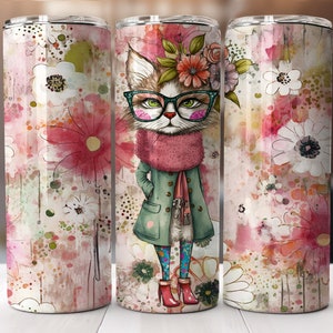 Op de afbeelding: Een roestvrijstalen tumbler met een roze en wit aquarel bloemenontwerp met een kat die een bril en een groene jas draagt.