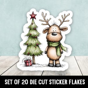 Könnte beinhalten: Ein gestanzter Aufkleber mit einem Cartoon-Rentier mit grünem Schal neben einem geschmückten Weihnachtsbaum. Der Baum wird von einem roten Stern gekrönt, und ein verpacktes Geschenk befindet sich an seiner Basis. Der Text "SET OF 20 DIE CUT STICKER FLAKES" steht unten.