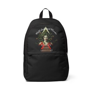May include: A black backpack featuring a graphic print of Medusa with green snakes for hair, wearing a red garment. Above the figure is the text Well Behaved Women and below is the text RARELY MAKE HISSSTORY, with a red triangle behind the word RARELY.