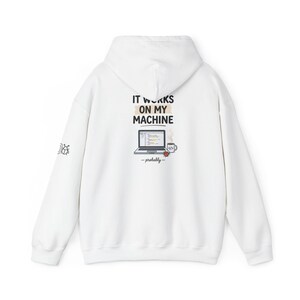 Könnte beinhalten: Ein weißer Kapuzenpullover mit einer Grafik auf der Rückseite, die den Text IT WORKS ON MY MACHINE, einen Laptop, eine Kaffeetasse mit Codesymbol und das Wort -probably- zeigt. Auf dem rechten Ärmel ist ein kleiner Käfer abgebildet.