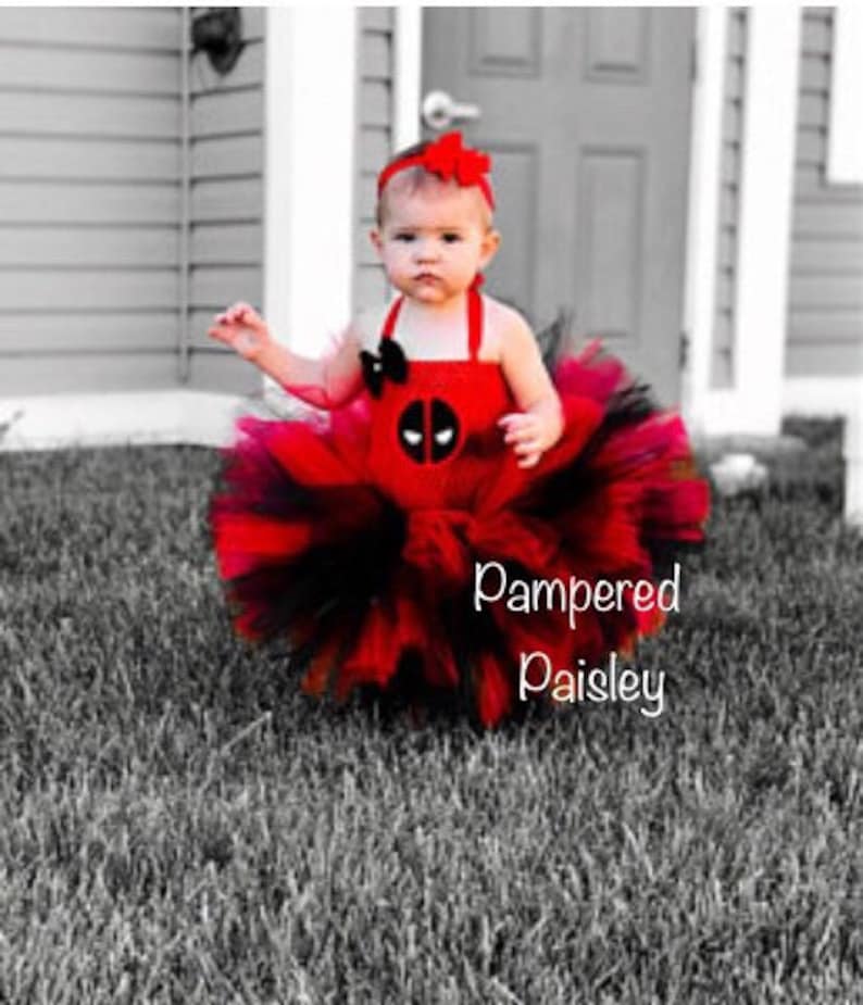 K&ouml;nnte beinhalten: Ein rot-schwarzes Tutu-Kleid mit einem Deadpool-Charakter-Emblem auf dem Oberteil, einem passenden roten Stirnband mit Schleife und einem mehrlagigen T&uuml;llrock. Der Text Pampered Paisley ist unten rechts im Bild zu sehen.