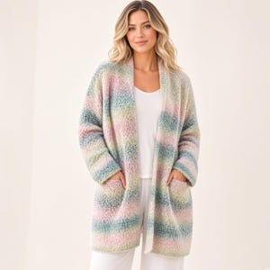 Può includere: Un cardigan a maniche lunghe aperto sul davanti con un motivo a righe orizzontali multicolore in delicate tonalità di rosa, verde, blu e giallo. Il capo è realizzato in un tessuto a maglia testurizzato e soffice, con due ampie tasche frontali.