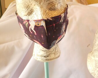 May include: A face mask with a dark purple background and a white unicorn print. The mask has pink stitching and a white star on the unicorn's horn.