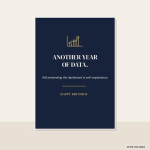 May include: A dark navy blue rectangular greeting card featuring a gold line-art bar graph icon at the top. The text reads: ANOTHER YEAR OF DATA. Still pretending the dashboard is self-explanatory. HAPPY BIRTHDAY. The card has a clean, modern design.