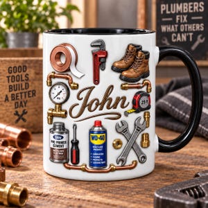 Puede incluir: Una taza de cerámica blanca con asa e interior negros, que presenta un estampado de herramientas de fontanería que incluye una llave inglesa, tuberías de cobre, un manómetro, una cinta métrica, botas de trabajo, un destornillador y botes de Oatey y WD-40, con el nombre John en cursiva.