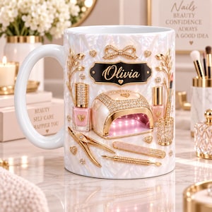 Könnte beinhalten: Ein weißer Keramikbecher mit Perlmutteffekt und einem schwarzen Schild in der Mitte, das den Namen Olivia in goldener Schrift zeigt. Das Design umfasst Abbildungen einer Nagellampe, rosa Nagellack, goldene Nagelwerkzeuge und kleine Schleifen.