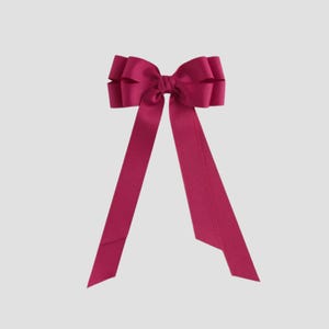 May include: A vibrant magenta bow with long, flowing tails. The bow features a layered design at the center, creating a full and textured appearance. The ribbon is a solid color, adding a touch of elegance. Perfect for hair accessories or gift wrapping.