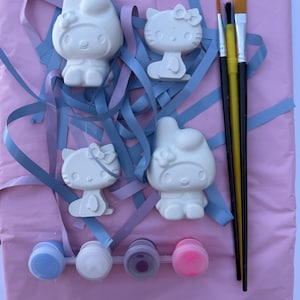 以下が含まれることがあります： ウサギのようなキャラクターの白い陶器製フィギュア2体と、猫のようなキャラクターの白い陶器製フィギュア2体、3本の絵筆、そして青、白、紫、ピンクの塗料が入った4つの小さな絵の具ポットがセットになったクラフトキット。