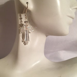 May include: Crystal angel dangle earrings with a silver tone finish. The earrings are made with clear crystal beads and have a delicate design.