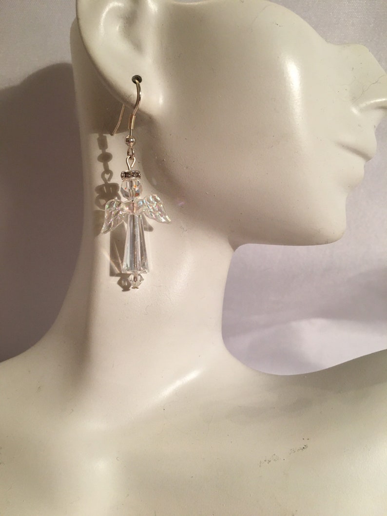 May include: Crystal angel dangle earrings with a silver tone finish. The earrings are made with clear crystal beads and have a delicate design.