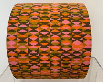Può includere: Un tessuto arrotolato con un motivo geometrico in tonalità di rosa, arancio e verde.