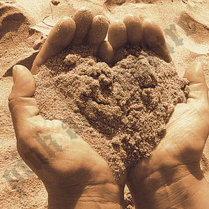May include: Two hands cupped together holding a heart shape made of sand. The sand is a light brown color and the hands are bare.