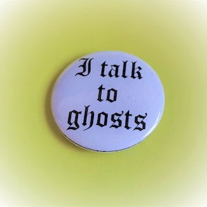 May include: White button with black text that reads "I talk to ghosts".