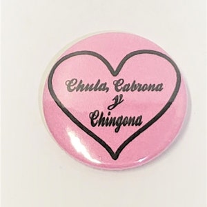 May include: Pink button with a black heart and the text "Chula, Cabrona y Chingona" inside.