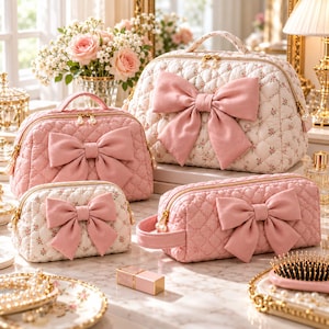 May include: A collection of four quilted cosmetic bags in shades of pink and cream with floral patterns. Each bag features a large, solid pink fabric bow on the front, gold-tone zippers with pearl-like pulls, and a soft, diamond-stitched texture.
