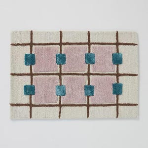 A horizontal orientation of the geometric hand-tufted rug displaying the mauve, teal, brown, and cream checkerboard grid design.