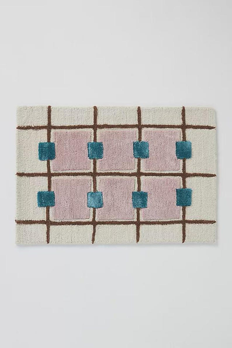 A horizontal orientation of the geometric hand-tufted rug displaying the mauve, teal, brown, and cream checkerboard grid design.