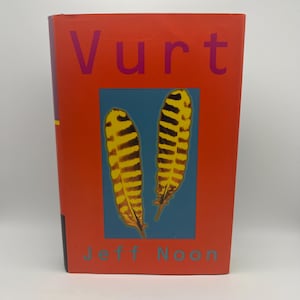 Puede incluir: Un libro de tapa dura titulado Vurt de Jeff Noon con una cubierta de color naranja brillante. La parte frontal presenta un recuadro rectangular azul central que muestra dos plumas rayadas amarillas y negras. El título está impreso en letras moradas grandes.