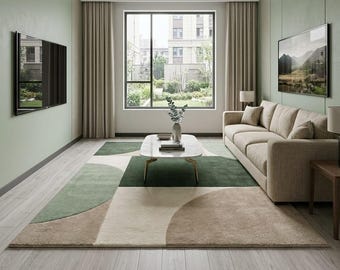 Puede incluir: Una alfombra rectangular con un patrón geométrico de grandes círculos y bloques superpuestos en tonos verde salvia, beige y crema. La alfombra tiene un pelo suave y texturizado, colocada sobre un suelo de madera clara en una sala de estar.