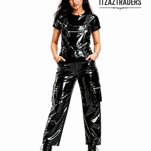 Peut inclure: Une combinaison salopette en vinyle noir brillant avec un haut à manches courtes, une poche poitrine zippée avec une tirette circulaire et deux grandes poches cargo zippées sur les jambes. Elle comprend des bretelles et des bottes noires.