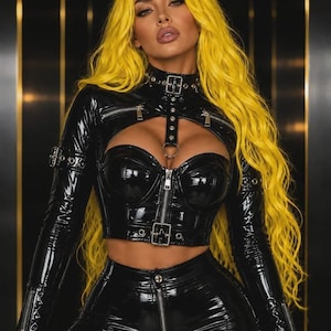 May include: A black patent leather-look cropped top featuring long sleeves, a high collar with a buckle, and a front zip closure. The garment includes a chest cutout, silver-toned hardware, and adjustable buckle straps on the sleeves and waist.