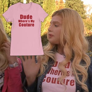 以下が含まれることがあります： 前面に「Dude Where's My Couture」という赤い太字のテキストがプリントされた、ライトピンクの半袖Tシャツ。この衣類は、クラシックなクルーネックとストレートな裾が特徴で、シンプルでクリーンなデザインに仕上がっています。