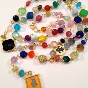 May include: A colorful beaded necklace with a gold chain and a small framed image of a person. The beads are made of various gemstones, including amethyst, turquoise, and carnelian. The necklace is approximately 30 inches long.