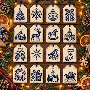 Puede incluir: Dieciséis etiquetas de regalo rectangulares de color crema con patrones de punto de cruz azul oscuro de iconos navideños, que incluyen un árbol de Navidad, copo de nieve, adorno, campanas, cabaña, reno, caballito de balancín, vela, estrella, pájaro, calcetín, corona, regalo, iglesia y trineo.