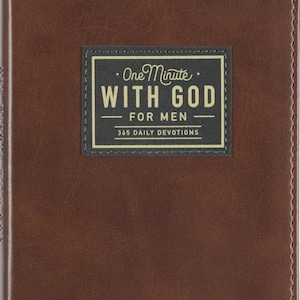 May include: A brown, leather-textured devotional book with a rectangular black label on the front cover. The label features the text "One Minute WITH GOD FOR MEN 365 DAILY DEVOTIONS" in white and gold lettering with a thin gold border.