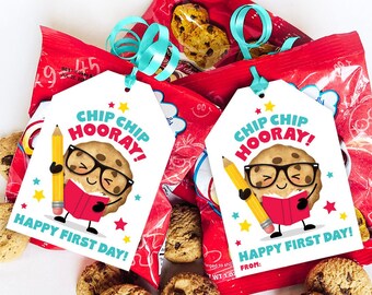 May include: Two red snack bags with blue ribbon and tags that read "Chip Chip Hooray! Happy First Day!" with a cartoon cookie character. Chocolate chip cookies are scattered around the bags.