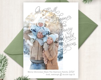 May include: A Christmas card featuring a family of three in winter clothing. The card has a handwritten message that reads "A thrill of hope, the weary world rejoices". The card also includes the text "Merry Christmas from The Harrison Family 2021 Josh, Ashleigh & Archie (age 1)"