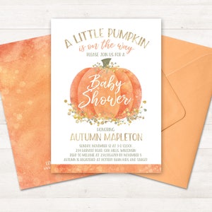 Może przedstawiać: Białe zaproszenie na baby shower z akwarelową ilustracją dyni i złotymi błyskotkami. Tekst brzmi "A Little Pumpkin is on the Way" i "Baby Shower". Zaproszenie jest dla Autumn Mapleton i zawiera datę, godzinę, miejsce i informacje RSVP.