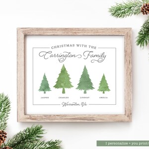 May include: A framed print with a light wood frame. The print features watercolor-style green Christmas trees with family names below. Text reads "Christmas with the Carrington Family" and "Warrenton, Va."