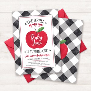 May include: A black and white checked invitation with a red apple illustration. The text reads "The apple of my eye Ruby Jane is turning one! Join us for a bushel of fun! Saturday, October 12 at 3 o'clock Harvest Hill Orchard & Petting Zoo 345 Orchard Lane, Richmond Please RSVP to 234.555.6789 by October 8"