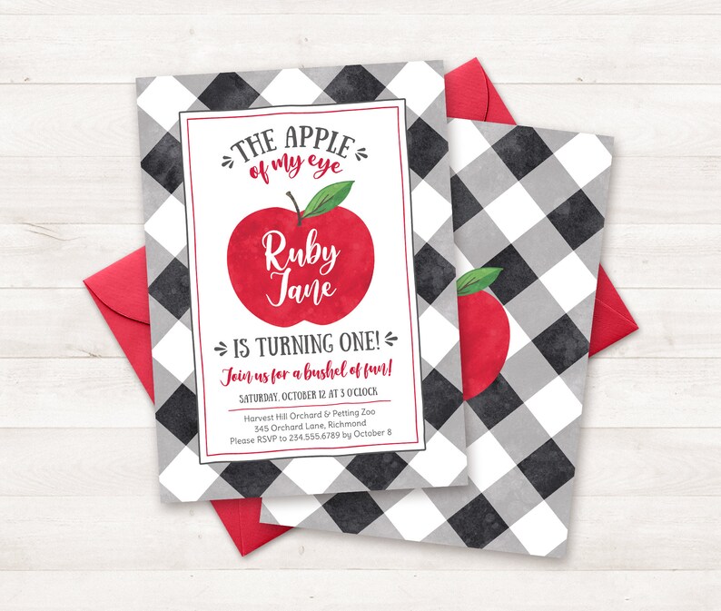 May include: A black and white checked invitation with a red apple illustration. The text reads "The apple of my eye Ruby Jane is turning one! Join us for a bushel of fun! Saturday, October 12 at 3 o'clock Harvest Hill Orchard & Petting Zoo 345 Orchard Lane, Richmond Please RSVP to 234.555.6789 by October 8"
