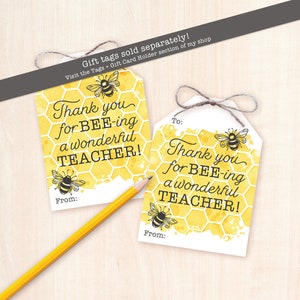 May include: Two yellow and white gift tags with a bee and honeycomb pattern. The text on the tags reads "Thank you for BEE-ing a wonderful TEACHER!" and "From:".