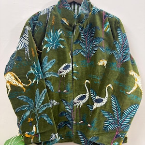 May include: A long-sleeve olive green jacket featuring a vibrant jungle-themed print. The pattern includes illustrations of zebras, leopards, and white long-necked birds interspersed with tropical palm trees and various green foliage.
